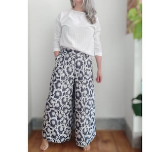 May include: A white long-sleeved blouse with a scoop neck and a pair of wide-leg pants with a black and white floral print.