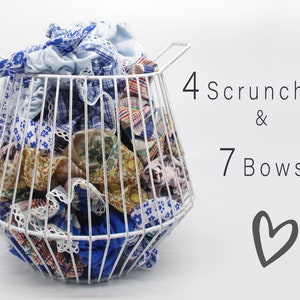 May include: A white wire basket filled with colorful fabric scrunchies and bows. The text "4 Scrunchies & 7 Bows" is written in black on a white background.