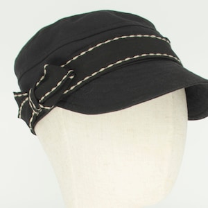 Pode incluir: Um bon&eacute; de algod&atilde;o preto com uma borda branca costurada e um la&ccedil;o preto no lado.