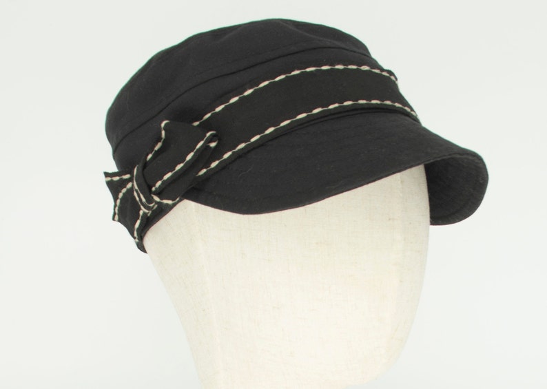 Pode incluir: Um bon&eacute; de algod&atilde;o preto com uma borda branca costurada e um la&ccedil;o preto no lado.