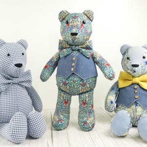 May include: Three stuffed teddy bears. The left bear is blue and white gingham with a matching bow tie. The center bear features a floral pattern with a blue vest and bow tie. The right bear has a patterned body, blue vest, and yellow bow tie.
