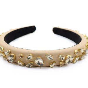 May include: A beige headband with clear rhinestones of various sizes and shapes.