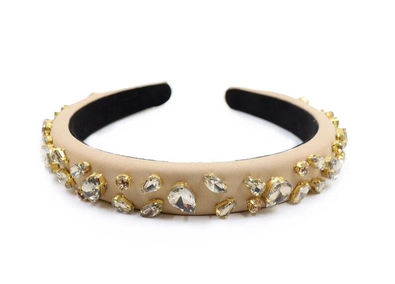 May include: A beige headband with clear rhinestones of various sizes and shapes.