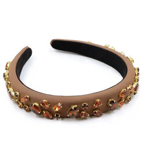 May include: A brown headband with a wide band and a row of gold and brown rhinestones.