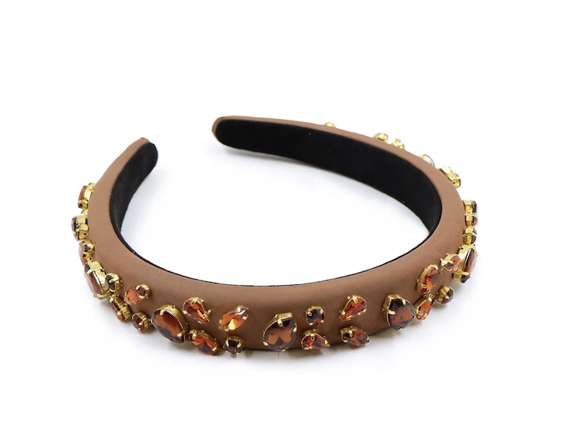 May include: A brown headband with a wide band and a row of gold and brown rhinestones.