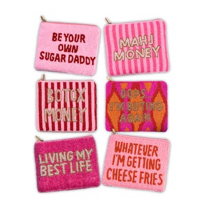 K&ouml;nnte beinhalten: Sechs pinkfarbene, perlenbesetzte M&uuml;nztaschen mit goldenen Rei&szlig;verschl&uuml;ssen. Jede Tasche hat einen anderen Satz in Gold- oder roten Perlen: "BE YOUR OWN SUGAR DADDY", "MAHJ MONEY", "BOTX MONEY", "OOPS I'M BUYING AGAIN", "LIVING MY BEST LIFE" und "WHATEVER I'M GETTING CHEESE FRIES".