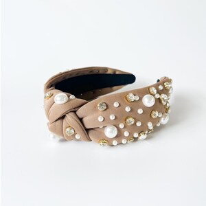 May include: A brown knotted headband with pearl and rhinestone embellishments.