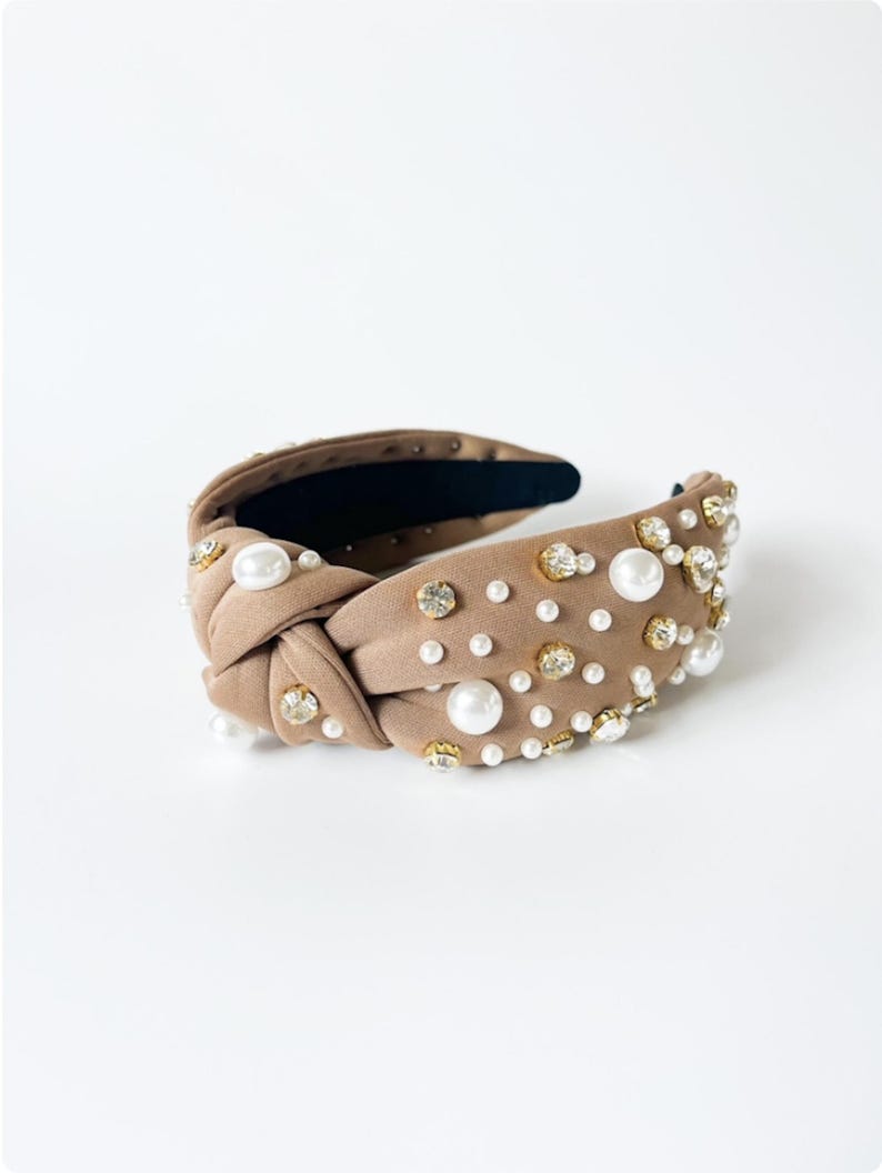 May include: A brown knotted headband with pearl and rhinestone embellishments.