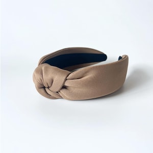 May include: A brown knotted headband with a black elastic band on the inside.