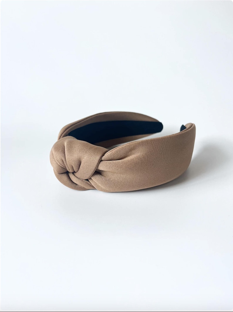 May include: A brown knotted headband with a black elastic band on the inside.