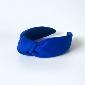 Puede incluir: Una diadema azul brillante con un dise&ntilde;o anudado. La diadema est&aacute; hecha de un material suave y aterciopelado y es de un color s&oacute;lido y llamativo. El accesorio est&aacute; dise&ntilde;ado para ser usado en la cabeza.