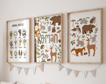 May include: Three framed art prints with woodland animal illustrations and the name "Roman". The prints feature a variety of animals, including bears, deer, and rabbits, along with animal tracks. The artwork is displayed above a wooden storage unit with white bins.