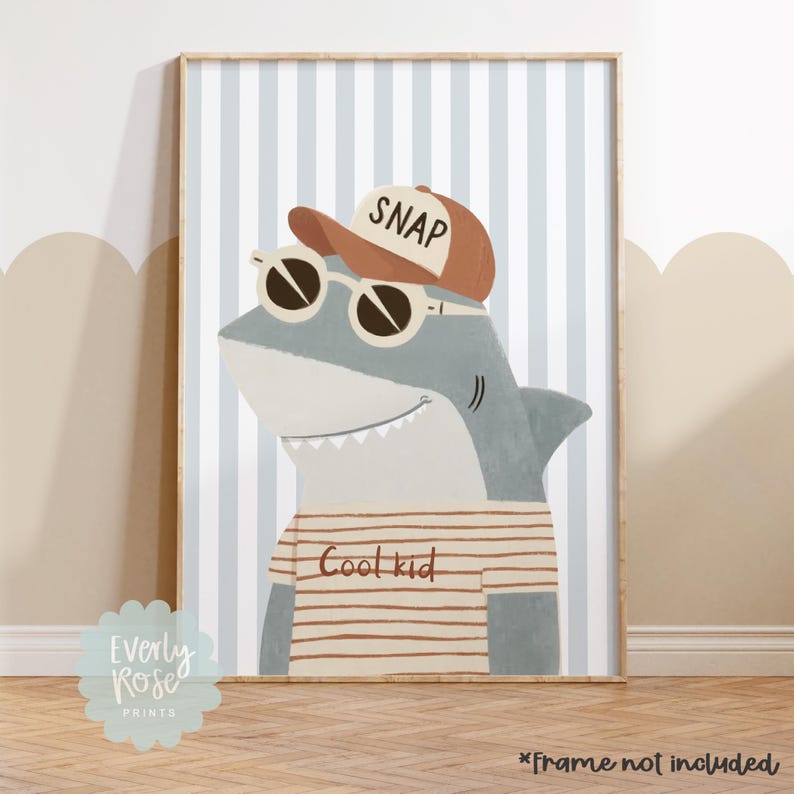 May include: A framed print featuring a cartoon shark wearing sunglasses and a baseball cap that says "SNAP." The shark is wearing a striped shirt that says "Cool kid." The background has blue and white vertical stripes.