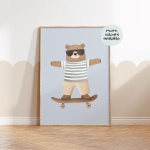 May include: A brown bear wearing sunglasses and a striped shirt is skateboarding on a light blue background. The text "more colours available" is in a circle at the top right of the image.
