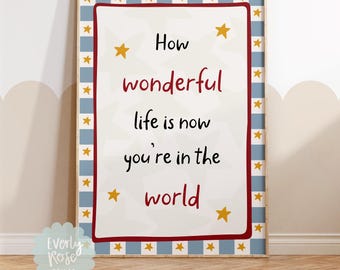 May include: A framed print with the words "How wonderful life is now you're in the world." The text is in black and red on a white background, surrounded by a red border and a blue and white star pattern.
