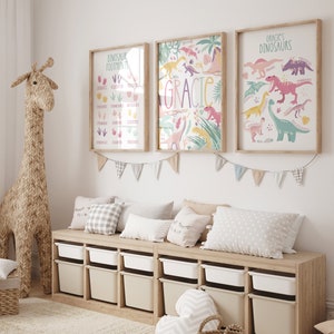 May include: A light wood storage bench with six white storage bins. The bench is decorated with three framed dinosaur-themed prints. The prints feature a pink and green color scheme and include the text "Gracie's Dinosaurs", "Dinosaur Footprints", and "Gracie".