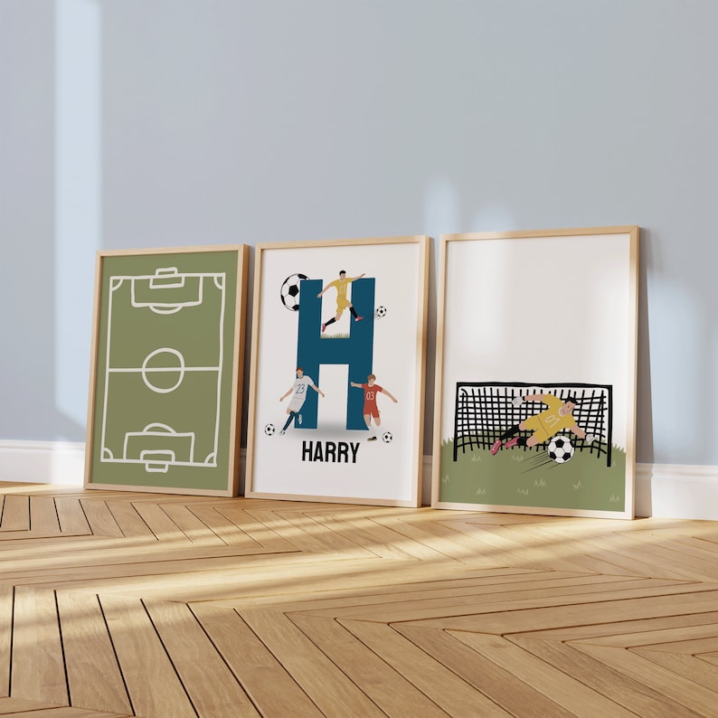 May include: Three framed prints with a soccer theme. The first print shows a green soccer field with white lines. The second print shows the letter H in blue with a soccer player kicking a ball. The text "HARRY" is below the letter. The third print shows a soccer player diving to save a goal.
