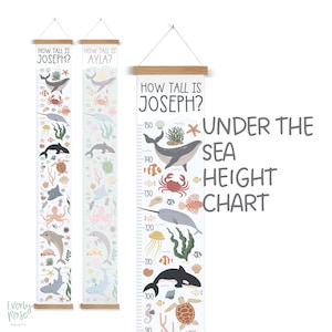 May include: A white and blue under the sea themed height chart with a wooden frame. The chart features a variety of sea creatures, including a whale, a narwhal, a jellyfish, a sea turtle, and a crab. The chart is labelled "How Tall Is Joseph?" and "Under The Sea Height Chart".
