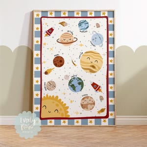 May include: A framed print depicting the planets of the solar system, each with a smiling face. The print has a blue and white striped border with gold stars. The text "Everly Rose Prints" is in the bottom left corner. The planets are labeled.