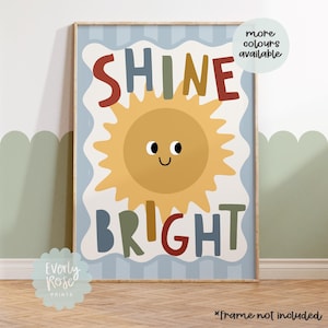 Puede incluir: Una impresi&oacute;n art&iacute;stica enmarcada con una ilustraci&oacute;n de sol alegre y las palabras "SHINE BRIGHT" en letras coloridas. La impresi&oacute;n tiene un fondo azul claro con rayas verticales y un borde blanco. Una burbuja de texto dice "more colours available".