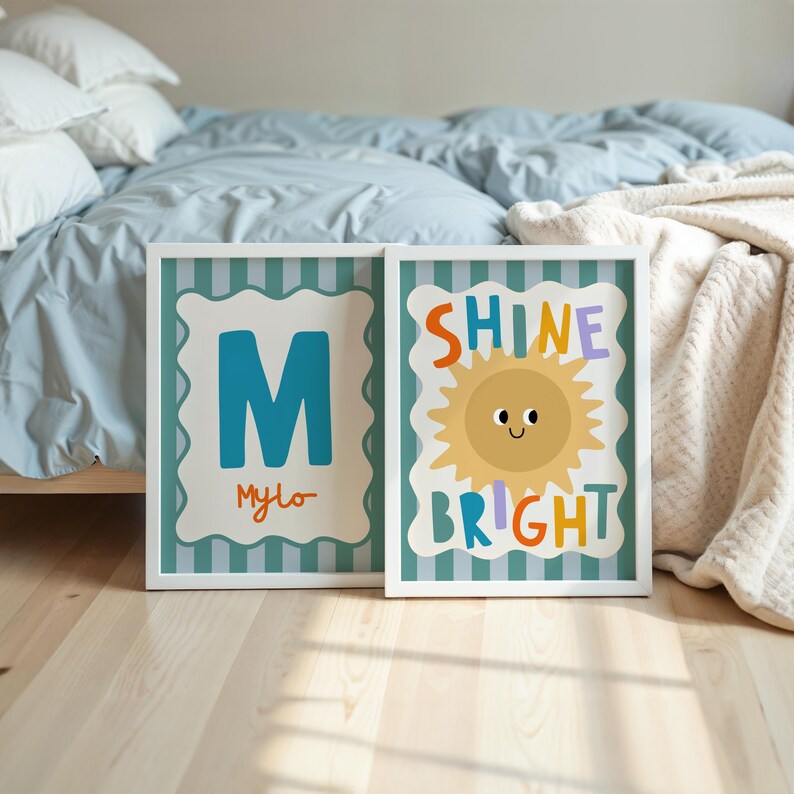 Puede incluir: Dos impresiones art&iacute;sticas enmarcadas. Una presenta la letra "M" turquesa con el nombre "Mylo" en naranja. La otra dice "Shine Bright" con una ilustraci&oacute;n de sol sonriente. Ambas tienen marcos blancos y fondos a rayas turquesas.