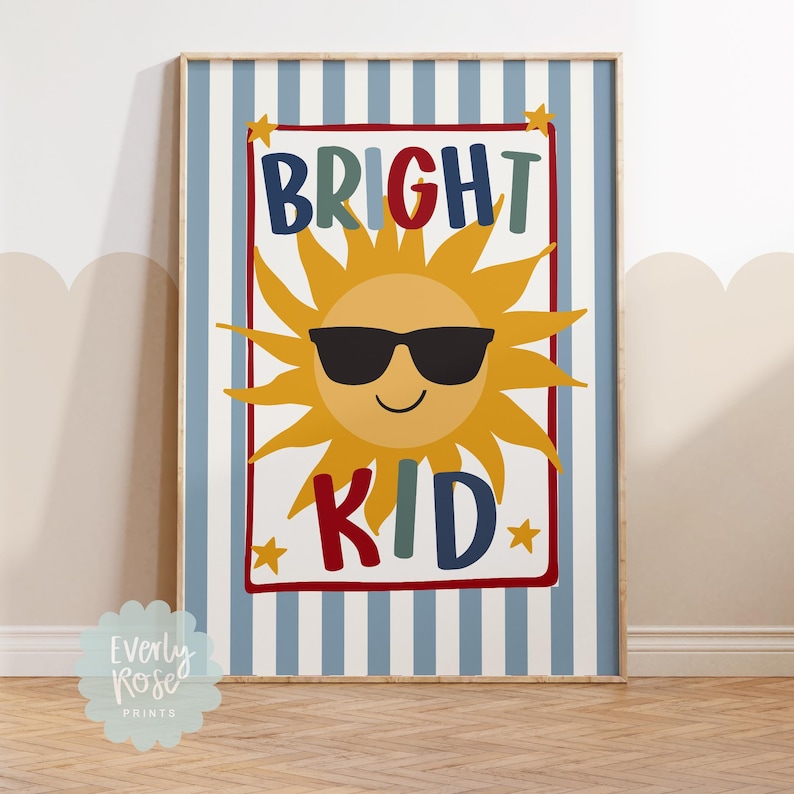 May include: A framed print with a blue and white striped background. The print features a smiling sun wearing sunglasses, with the words "BRIGHT KID" in colorful letters. Small yellow stars are in each corner of the text.
