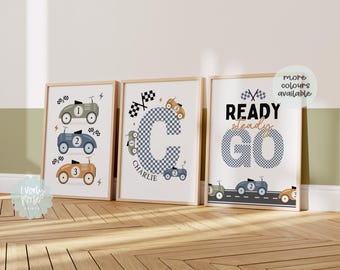 May include: Three framed prints with a racing car theme. The first print features a blue and green car with the number 1, the second print features a blue and white checkered letter C with the name Charlie, and the third print features the words Ready Steady Go in blue and white checkered letters.