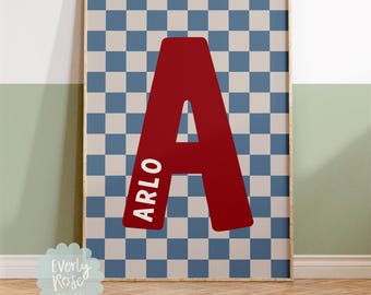 May include: Framed print featuring a large red letter "A" with the name "ARLO" in white text. The background is a blue and beige checkered pattern. The print is from Everly Rose Prints. The text "*Frame not included" is at the bottom.