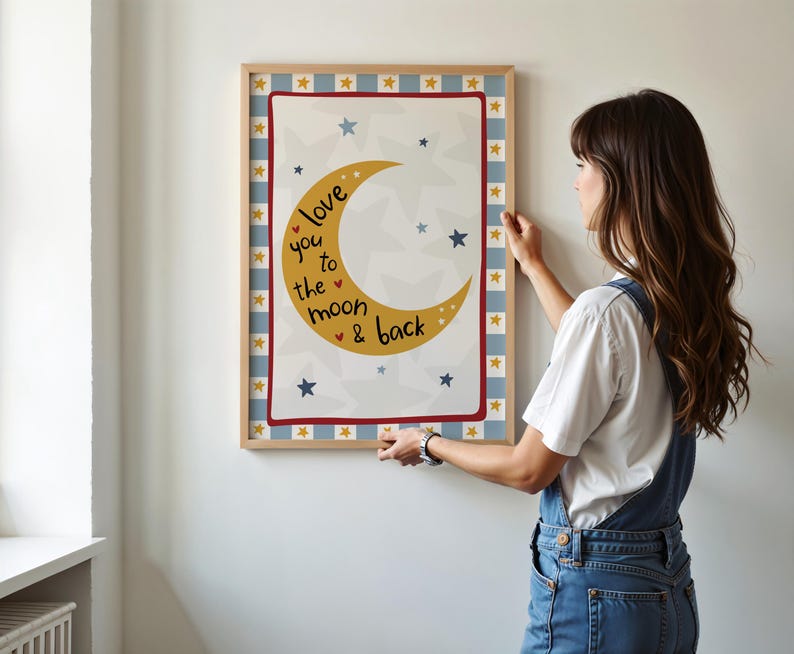 K&ouml;nnte beinhalten: Ein gerahmter Druck mit einem gelben Halbmond und Sternen, mit dem Text "love you to the moon & back". Der Druck hat einen rot-blauen Rand mit einem hellen Holzrahmen. Der Hintergrund ist wei&szlig;.