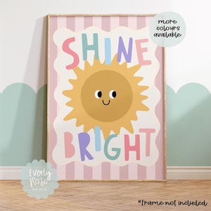 Puede incluir: Una impresi&oacute;n art&iacute;stica enmarcada con las palabras "SHINE BRIGHT" en letras coloridas, con una ilustraci&oacute;n de un sol sonriente. El fondo tiene rayas rosas y blancas. El texto "more colours available" est&aacute; en un c&iacute;rculo blanco.
