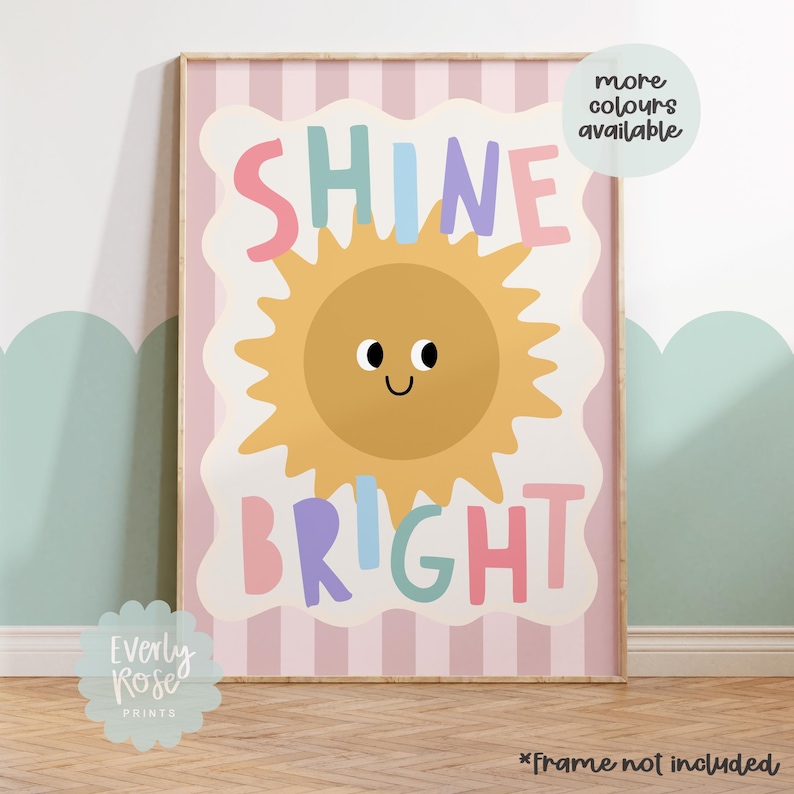 Puede incluir: Una impresi&oacute;n art&iacute;stica enmarcada con las palabras "SHINE BRIGHT" en letras coloridas, con una ilustraci&oacute;n de un sol sonriente. El fondo tiene rayas rosas y blancas. El texto "more colours available" est&aacute; en un c&iacute;rculo blanco.