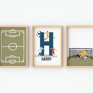 May include: Three framed prints with a soccer theme. The first print shows a green soccer field with white lines. The second print shows the letter H in blue with soccer players in yellow and white uniforms. The third print shows a soccer player in a yellow uniform diving to save a goal. The text "HARRY" is below the letter H.