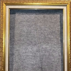 May include: A gold picture frame with a white mat and a gray background.