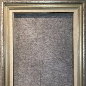 May include: A silver and gold picture frame with a textured surface. The frame has a cream-colored mat.