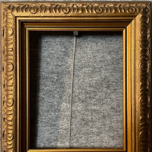 May include: A gold picture frame with an ornate design. The frame is empty and ready to display a photo or artwork.