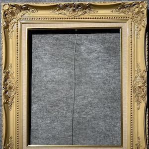 May include: A gold ornate picture frame with a cream-colored mat and a textured surface. The frame has a decorative design with intricate details.