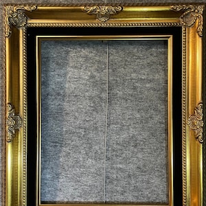 May include: A gold picture frame with a black mat. The frame has ornate details and a beaded border.