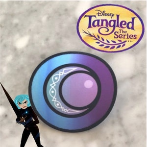 Peut inclure: Un patch circulaire bleu et violet avec un motif de croissant de lune blanc. Le patch a une bordure blanche et un motif blanc à l'intérieur du croissant de lune. Le patch est de la série Disney Tangled.