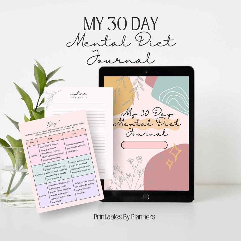 Op de afbeelding: Een digitale tablet en een gedrukt journaal met de tekst "MY 30 DAY Mental Diet Journal". De tablet toont een journaalpagina met bloemaccenten. Een gedrukte pagina toont een dagelijkse planning met tijdsblokken en taken. Het kleurenpalet omvat roze, beige en teal.