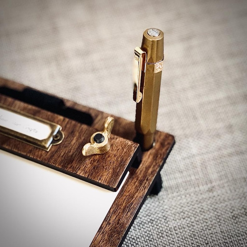 May include: A wooden desk organizer with a brass knob and a gold pen holder. The organizer has a small notepad and a brass nameplate that says "To Do List".