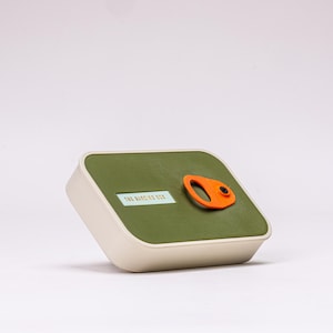 May include: A rectangular container with a rounded top and base. The top is olive green with an orange handle and the text "THE BARDING BOX". The base is off-white.