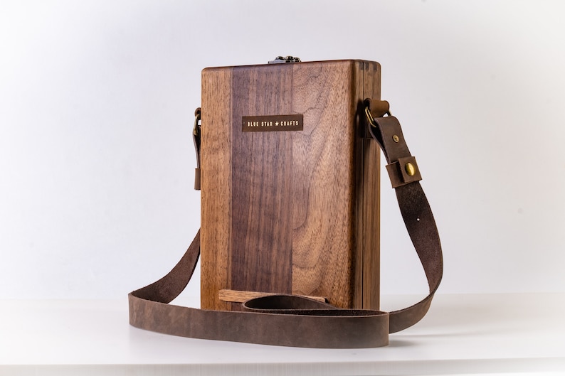 Puede incluir: Una caja de madera marr&oacute;n con una correa de cuero y una hebilla de lat&oacute;n. La caja tiene una etiqueta que dice "Blue Star Crafts".