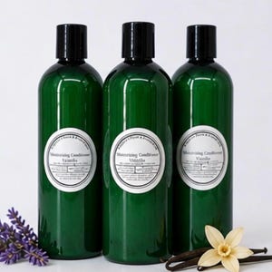 May include: Three green bottles of moisturizing conditioner with black caps and white labels. The labels read "Moisturizing Conditioner Vanilla". The image includes lavender, a vanilla flower, and vanilla beans.