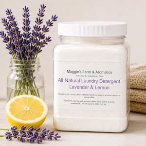 Puede incluir: Un frasco transparente de detergente para ropa natural con tapa blanca, etiquetado como "Lavanda y Lim&oacute;n". Una ramita de lavanda y media rodaja de lim&oacute;n est&aacute;n junto al frasco. La etiqueta incluye el texto "Maggie's Farm & Aromatics".