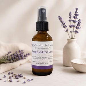 May include: An amber glass spray bottle labeled Maggie's Farm & Aromas Sleepy Pillow Spray with a black pump top. The label lists ingredients including distilled water, lavender, and chamomile essential oils, with a net weight of 2 fl oz (56.7 G).