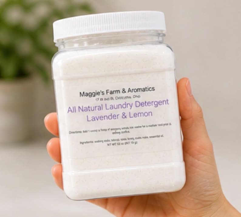 Puede incluir: Un recipiente rectangular transparente de detergente para ropa con tapa blanca, sostenido en una mano. La etiqueta dice "Maggie's Farm & Aromatics" y "All Natural Laundry Detergent Lavender & Lemon". El peso neto es de 340 gramos.