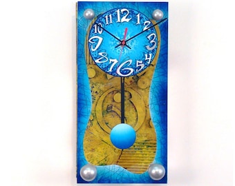 May include: A blue and yellow clock with a pendulum. The clock face is blue with white numbers and hands. The clock is surrounded by a yellow and blue design.