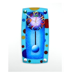May include: A decorative wall clock with a light blue rectangular frame. The clock face features colorful numbers and hands, with a pendulum and a blue orb at the bottom. The frame is adorned with colorful polka dots.