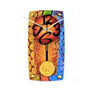 Puede incluir: Un reloj de pared abstracto y colorido con péndulo. La esfera del reloj es un círculo rojo, naranja y amarillo con números negros. El reloj está rodeado de un fondo azul, verde y dorado.