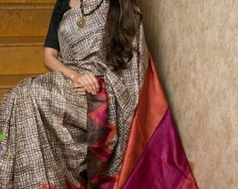 May include: A brown and white patterned silk saree with a pink, orange, and brown border. The saree is draped over a wooden staircase.
